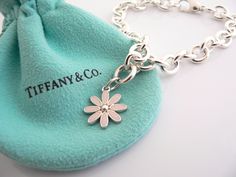 Overview: Here is a gift that she will surely adore! It is shiny, stylish, and super versatile! This piece will make someone REALLY happy! :) Offered for sale is a wonderful Tiffany & Co. Sterling Silver and Pink Enamel Daisy Charm Bracelet. Hanging from its bright Tiffany silver chain is a very pretty Pink Enamel Daisy charm! A classic Tiffany piece that any girl will adore! The Daisy charm hangs from its Sterling Silver Tiffany clasp - it is removable from the bracelet and thus allows you to w Designer Bracelets With Polished Finish For Gift, Designer Polished Finish Bracelets For Gift, Luxury Flower-shaped Bracelets As Gift, Daisy Flower Bracelet, Daisy Charm, Enamel Bangle, Pink Enamel, Flower Bracelet, Tiffany Heart