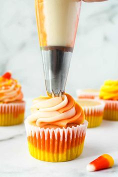 someone is decorating cupcakes with orange icing and white frosting on top