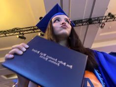 a woman in graduation cap and gown holding up a book