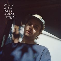 a man wearing a hat standing in front of a building with the words mac dem marco's also days written on it