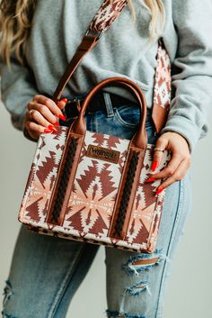 a woman is holding a brown and white handbag in her right hand while wearing ripped jeans