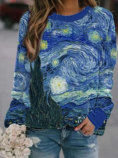 a woman wearing a blue sweater with the starry night painting on it, holding a bouquet of flowers