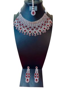 Indulge in elegance with our CZ American Diamond Choker Necklace set. Featuring stunning red stones, this set exudes luxury and sophistication. Elevate any outfit and make a statement with this beautiful choker necklace set. Instantly add a touch of glamour to your look. This jewellery set includes a necklace, matching earrings and a maang tika. Jewellery Care- Keep the jewellery dry, avoid contact with perfumes and water. Elegant Red Bridal Necklace With Sparkling Stones, Luxury Red Jewelry Sets For Wedding, Luxury Red Jewelry With Sparkling Stones, Glamorous Red Jewelry With Sparkling Stones, Red Ruby Choker Necklace, Red Cubic Zirconia Jewelry With Stones, Dazzling Red Necklaces With Sparkling Stones, Elegant Red Bridal Necklace For Party, Red Sparkling Stones Necklace For Formal Occasions