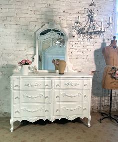 a white dresser sitting in front of a brick wall