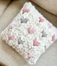 a crocheted pillow with hearts on it