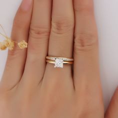 a woman's hand with two gold rings and a diamond ring on her finger