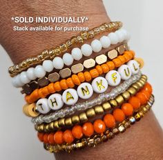 a stack of bracelets with the words happy written on them in gold, white and orange