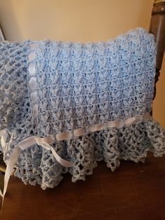 a blue crocheted pillow sitting on top of a wooden chair