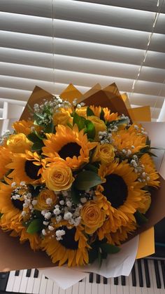 a bouquet of sunflowers and baby's breath sits on top of a piano