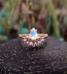 an opal and diamond ring sits on top of a rock