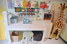 a giraffe standing next to a white desk in a child's room