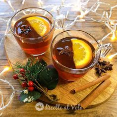 two glasses of mulled tea with orange slices and cinnamon on a wooden platter