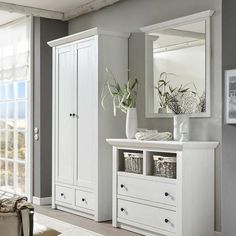 a white dresser sitting in a living room next to a window