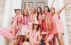 a group of young women in pink outfits posing for a photo with their hands up