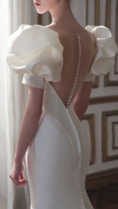 a woman in a white wedding dress is looking off into the distance with her back to the camera