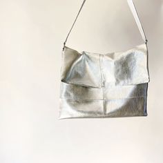 Every day is a party with something sparkly in hand. Butter soft metallic leather, with subtle checkerboard seaming, forms a bag that works day and night. A shoulder strap adds daytime convenience, and can be removed or tucked inside for a sleek clutch. Lined with supple suede for well deserved luxury. Hand sewn from full grain metallic leather, solid brass zipper and hardware. Made in the USA. Silver Leather Clutch Shoulder Bag, Silver Leather Shoulder Bag With Magnetic Closure, Silver Leather Shoulder Bag With Detachable Handle, Everyday Use Clutch Shoulder Bag With Silver-tone Hardware, Silver Leather Shoulder Bag For Party, Leather Square Clutch With Detachable Handle, Square Leather Clutch With Detachable Handle, Silver Rectangular Bag With Magnetic Closure, Silver Crossbody Shoulder Bag With Magnetic Closure