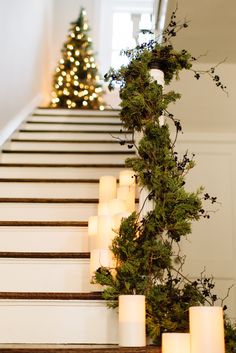 candles are lined up on the stairs in front of a christmas tree