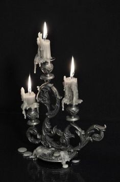 three candles are lit in the middle of a candle holder on a black tablecloth