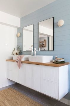 a bathroom with two sinks and mirrors on the wall next to a rug in front of it