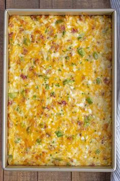 a casserole dish with cheese, green onions and other toppings on a wooden table