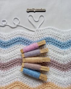 four crocheted wooden spools sitting on top of a knitted blanket