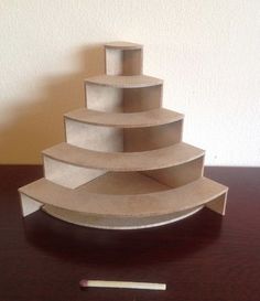 a model of a building made out of cardboard on top of a wooden table next to a white wall