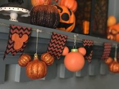 halloween decorations are hanging on the mantle with pumpkins and other decorations in the background