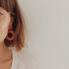 a close up of a person wearing earring's and a white t - shirt