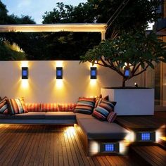 an outdoor seating area is lit up at night with lights on the walls and floor