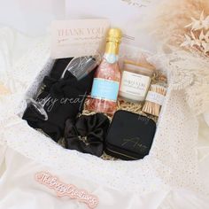 an open gift box containing champagne, wine and other personal care items on a bed