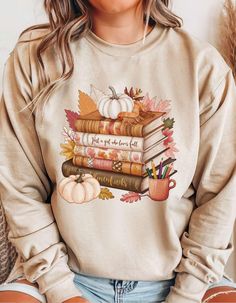 🍂 Fall Pumpkin Sweatshirt | Thanksgiving T-Shirt | Book Lover Shirt 🍁 Embrace the warmth and coziness of fall with this delightful pumpkin-themed sweatshirt! Perfect for those who love the autumn season, this soft and comfy sweatshirt captures the essence of fall with a charming pumpkin design. Whether you're spending time with family on Thanksgiving or curling up with a good book, this sweatshirt is just for you! Seasonal Style: Ideal for cool fall evenings and cozy days at home, keeping you warm and stylish. Pumpkin Love: Features a chic and minimal pumpkin design, the quintessential symbol of fall. Perfect for Book Lovers: A great gift for those who love reading, combining the joy of books and the beauty of autumn. Thanksgiving Ready: Complete your look for family gatherings or fall o Fall Bookish Tops With Graphic Print, Fall Graphic Print Bookish Tops, Relaxed Fit Bookish Sweatshirt For Fall, Fall Bookish T-shirt With Letter Print, Bookish Fall T-shirt With Letter Print, White Bookish Sweatshirt With Letter Print, Autumn Hoodie, Fall O, Sweat Women