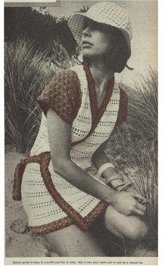 an old photo of a woman sitting on the beach wearing a crocheted dress and hat