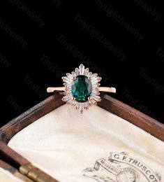 an emerald colored ring in a wooden box