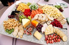 an assortment of cheeses, fruits and crackers on a platter