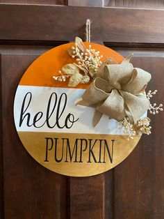 a wooden door with a sign that says hello pumpkin on it and a bow hanging from the front