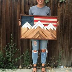 a woman is holding up a painting made out of wooden planks and wood strips