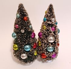 two small christmas trees with colorful ornaments on them