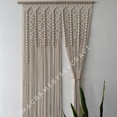 the wall hanging is made from macrame and has fringes attached to it