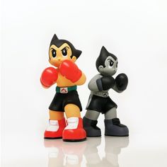 two toy figurines that are standing next to each other on a white surface