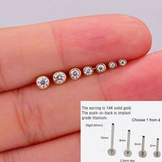 a person's hand holding three different sized diamond studs