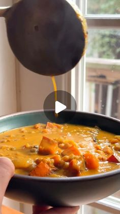 a person is pouring some soup into a bowl