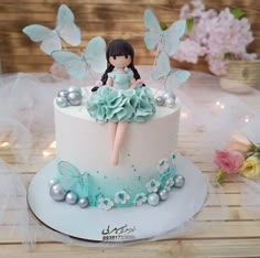 there is a cake decorated with a doll and butterflies on the top, sitting on a table