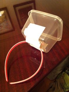 a plastic container sitting on top of a wooden table next to a red cord and framed pictures