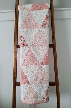 a pink and white quilt hanging on a ladder