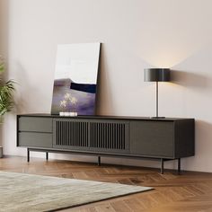 a living room with a large painting on the wall next to a wooden cabinet and lamp