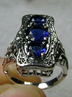 "Simulated Blue Sapphire Ring 3Stone Rectangle#60 Custom Made This is a lovely late Victorian era reproduction ring in solid sterling silver. The gorgeous filigree ring is set with 3 round-cut simulated blue sapphire gemstones. The 2 smaller blue sapphire gems are 4.5mm in diameter, and the center one is 6mm in diameter. This filigree setting is a casting from an actual Antique ring; notice the amazing etched band... The ring sits 3/4th\" (19mm) NS on the finger. The quality of the silver and ge Blue Multi-stone Sapphire Ring In Art Deco Style, Antique Three Stone Jewelry For Formal Occasions, Antique Three Stone Oval Jewelry, Antique Oval Three-stone Jewelry, Antique Three-stone Oval Jewelry, Classic Blue Three-stone Jewelry, Fine Jewelry Sapphire Three Stone, Art Deco Silver Sapphire Ring With Emerald Cut, Art Deco Multi-stone Sapphire Jewelry