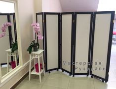 a room divider with flowers on it in front of a mirror and two mirrors