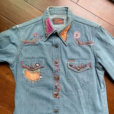 Rare Landlubber denim shirt with snaps up the front and on the cuffs. Dated 1960s/70s. Legit vintage. OOAK, handcrafted with embroidery, velvet patches, and rhinestone accents. This shirt is marked 16, which I think is a boy's size. It can be worn by a female or a smaller frame male. We have photographed it on male and female mannequins to show to different fit. The shirt wraps left over right closure.  Landlubber was one of the go-to denim labels in the 70s for its great innovative designs and fit.  Our pieces are legitimate vintage, one of a kind, one piece only for sale. LABEL: Original Landlubber, size 16 **Refer to measurements for an accurate fit.  SIZE: All sizing given is approximate.  MEASUREMENTS Shoulder: 16" Underarm: 42" Sleeve: neckline seam to cuff: 29 7/8" shoulder seam to Vintage Medium Wash Tops For Rodeo, Vintage Denim Top For Rodeo, Vintage Embroidered Tops For Rodeo, Shirt Patchwork, Embroidered Denim Shirt, Hippie Top, Embroidered Denim, Embroidery Patches, Small Frame