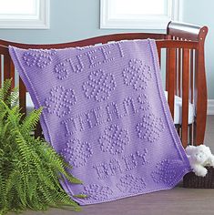 a crocheted blanket sitting on top of a wooden bench next to a potted plant