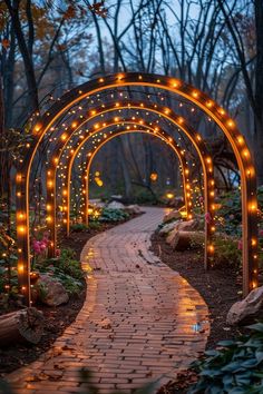 an arch with lights on it in the middle of a garden